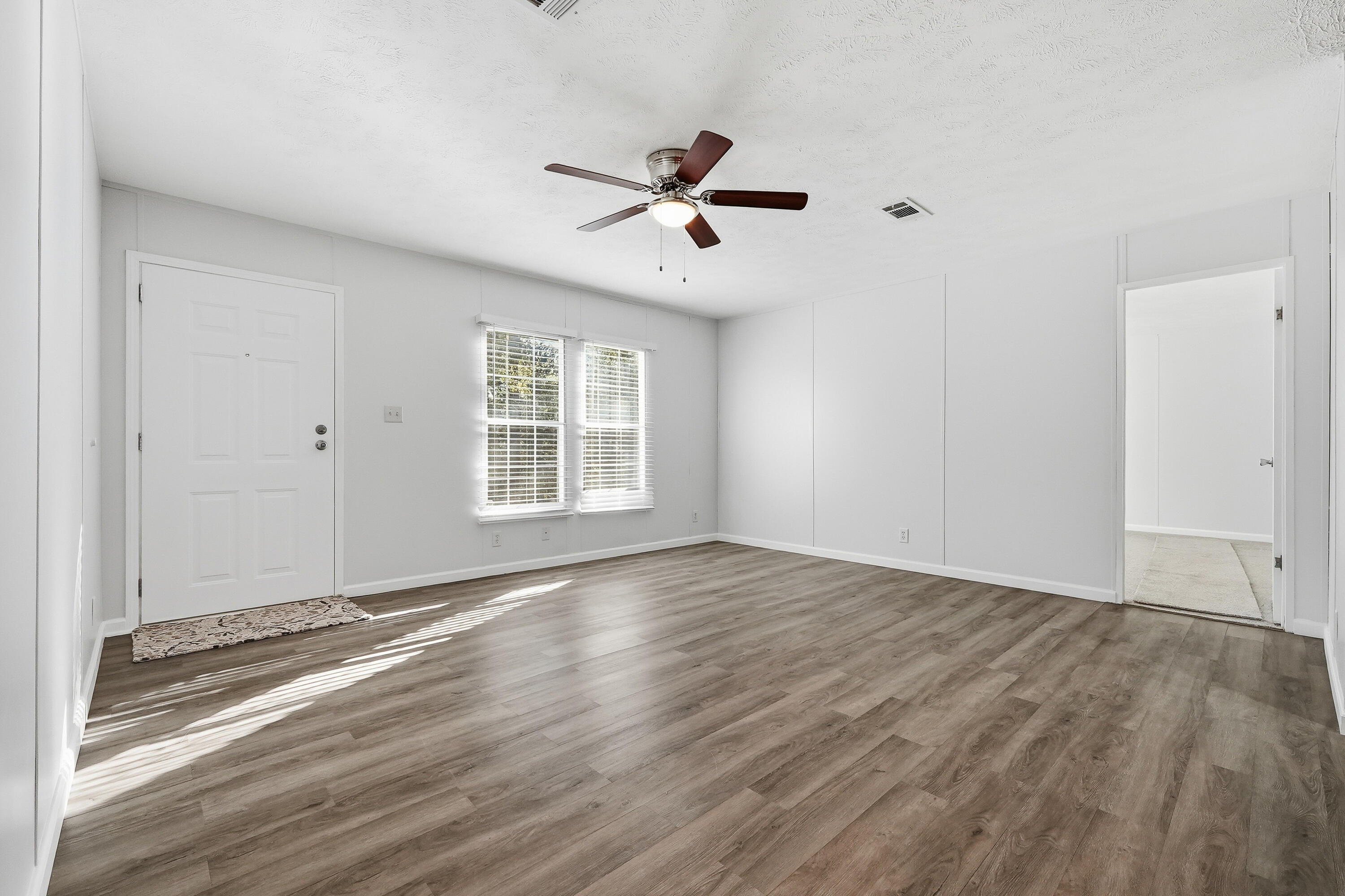 482 Roberts Road East DeFuniak Springs, FL 32433 - Photo 7 of 61 an empty room with wooden floor ceiling fan and windows