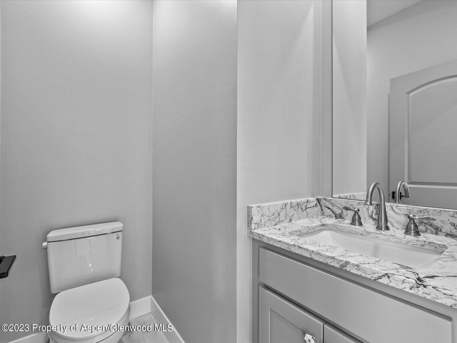 1416 Rifle Heights Drive Rifle, CO 81650 - Photo 23 of 35 a bathroom with a granite countertop toilet and a sink