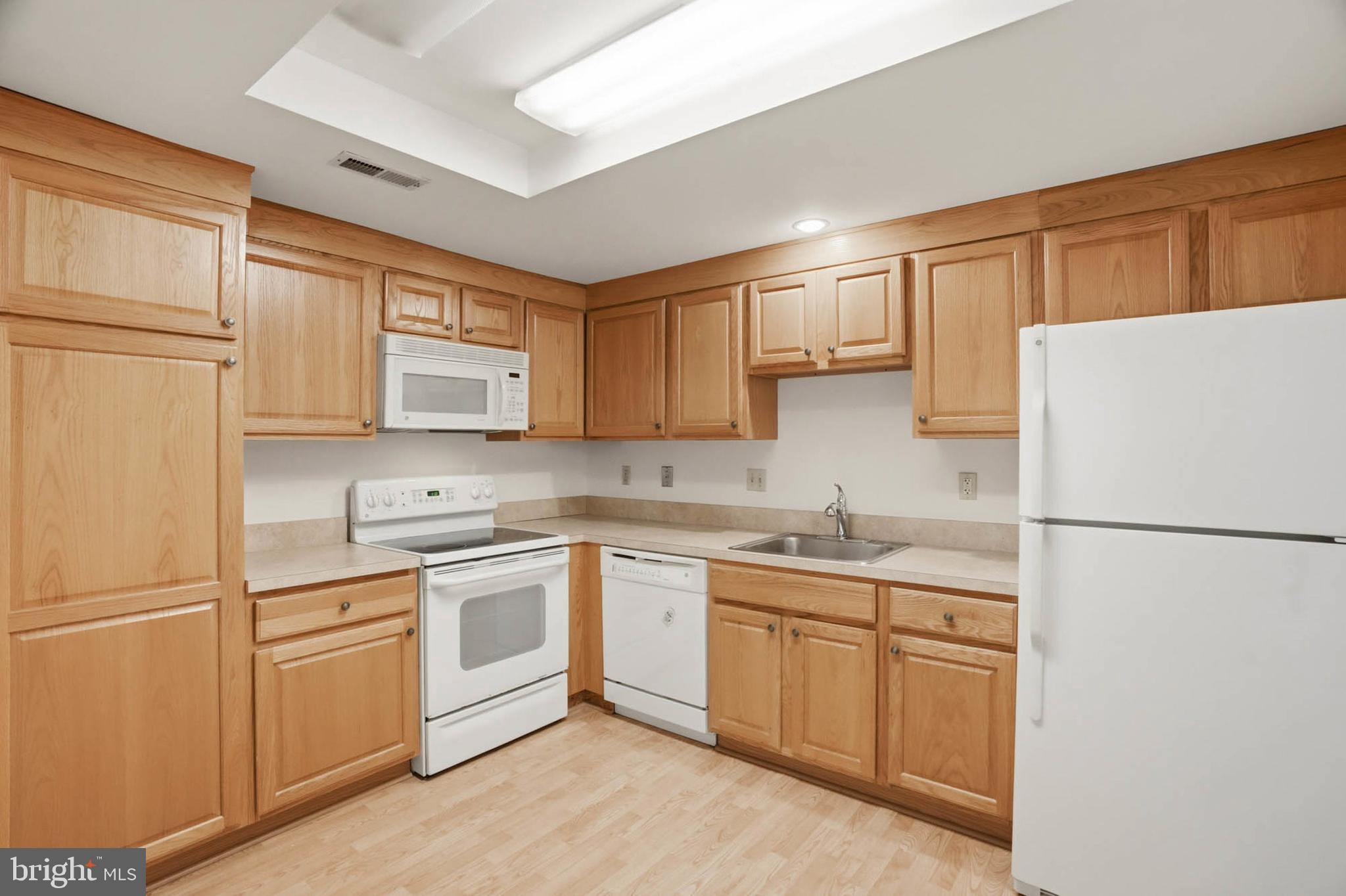 3501 Forest Edge Drive, Unit 142G Silver Spring, MD 20906 - Photo 12 of 30 a kitchen with a sink a refrigerator a microwave and cabinets