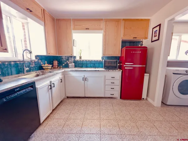 a kitchen with granite countertop a sink a stove a refrigerator a washer dryer and cabinets