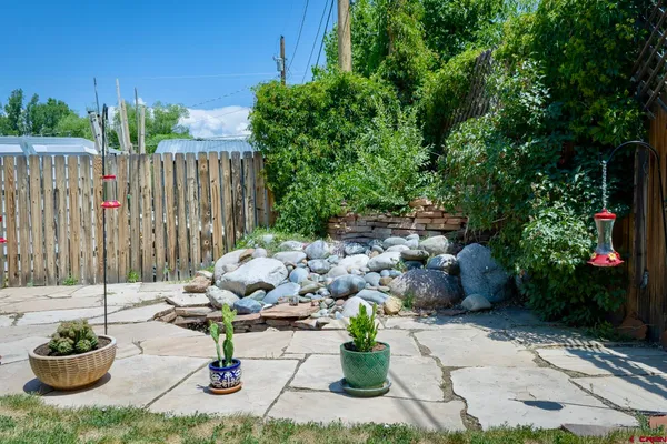 a view of a backyard with table and chairs potted plants and wooden fence
