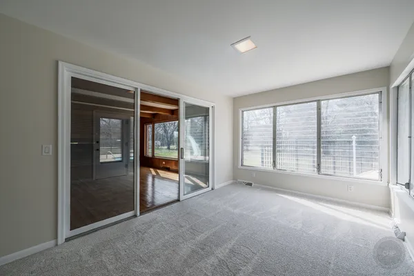 a view of an empty room with a window and wooden floor