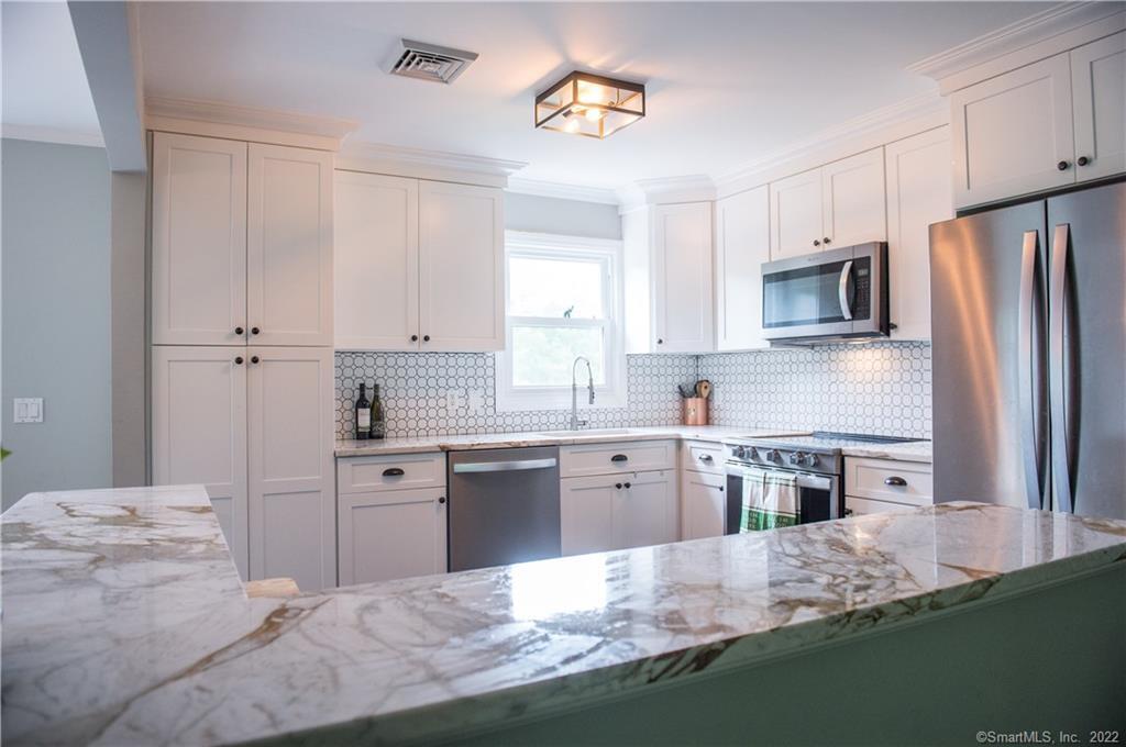 a kitchen with stainless steel appliances granite countertop a sink refrigerator stove and microwave