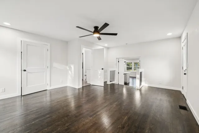a view of empty room with wooden floor and ceiling fan