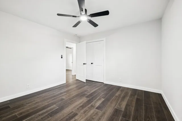 an empty room with wooden floor and ceiling fan