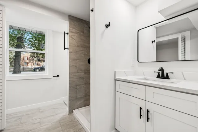 a bathroom with a granite countertop sink a mirror and shower