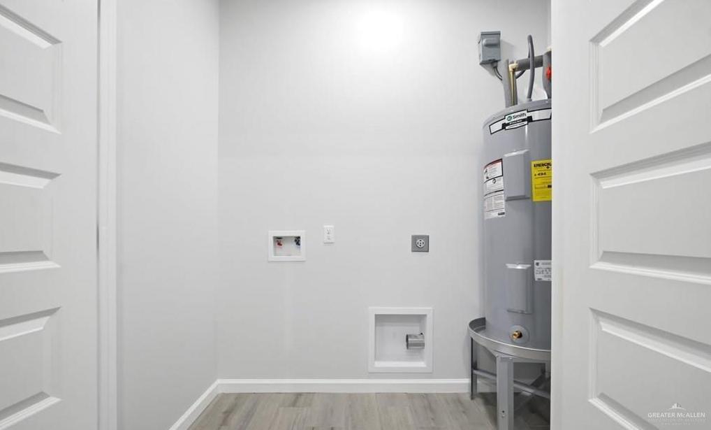 1604 Clinton Street, Unit 1 Harlingen, TX 78550 - Photo 5 of 14 Utility room featuring a water heater, washer/dryer hookups, and wood-finish flooring