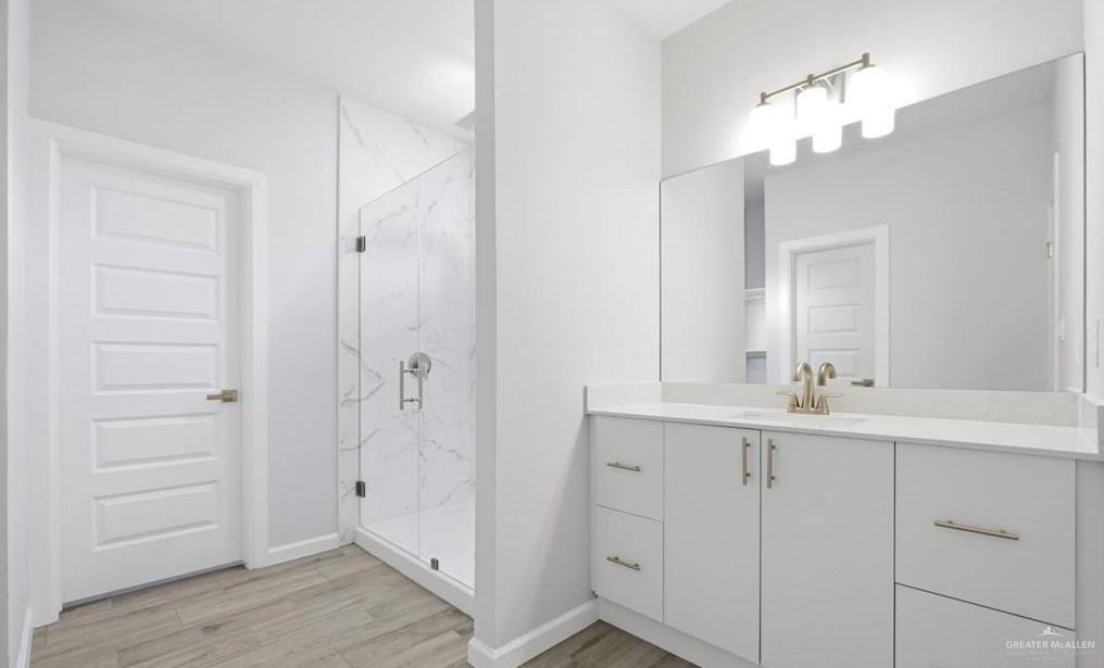 1604 Clinton Street, Unit 1 Harlingen, TX 78550 - Photo 9 of 14 Contemporary bathroom featuring a spacious walk-in shower with full height tile surround, dual sink vanity with quartz countertop, and large wall-mounted mirror