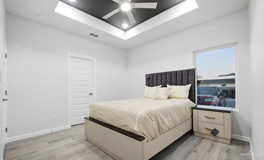 1604 Clinton Street, Unit 1 Harlingen, TX 78550 - Photo 10 of 14 Spacious bedroom featuring light wood-finish flooring, a tray ceiling with recessed lighting, and a ceiling fan
