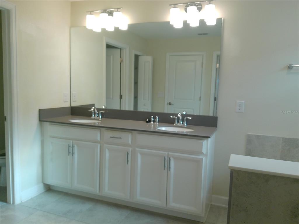 1146 Trappers Trail Loop Davenport, FL 33896 - Photo 18 of 31 a bathroom with a double vanity sink and a mirror