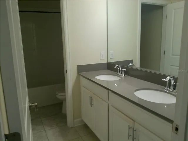 a bathroom with a granite countertop sink a toilet and a mirror