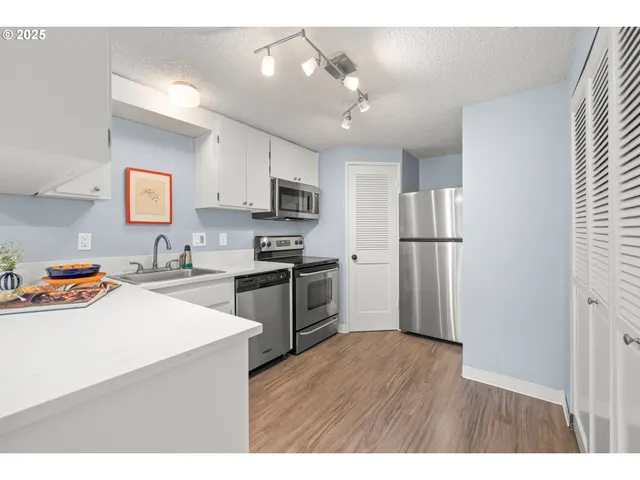 a kitchen with granite countertop a refrigerator a sink dishwasher and a stove with wooden floor