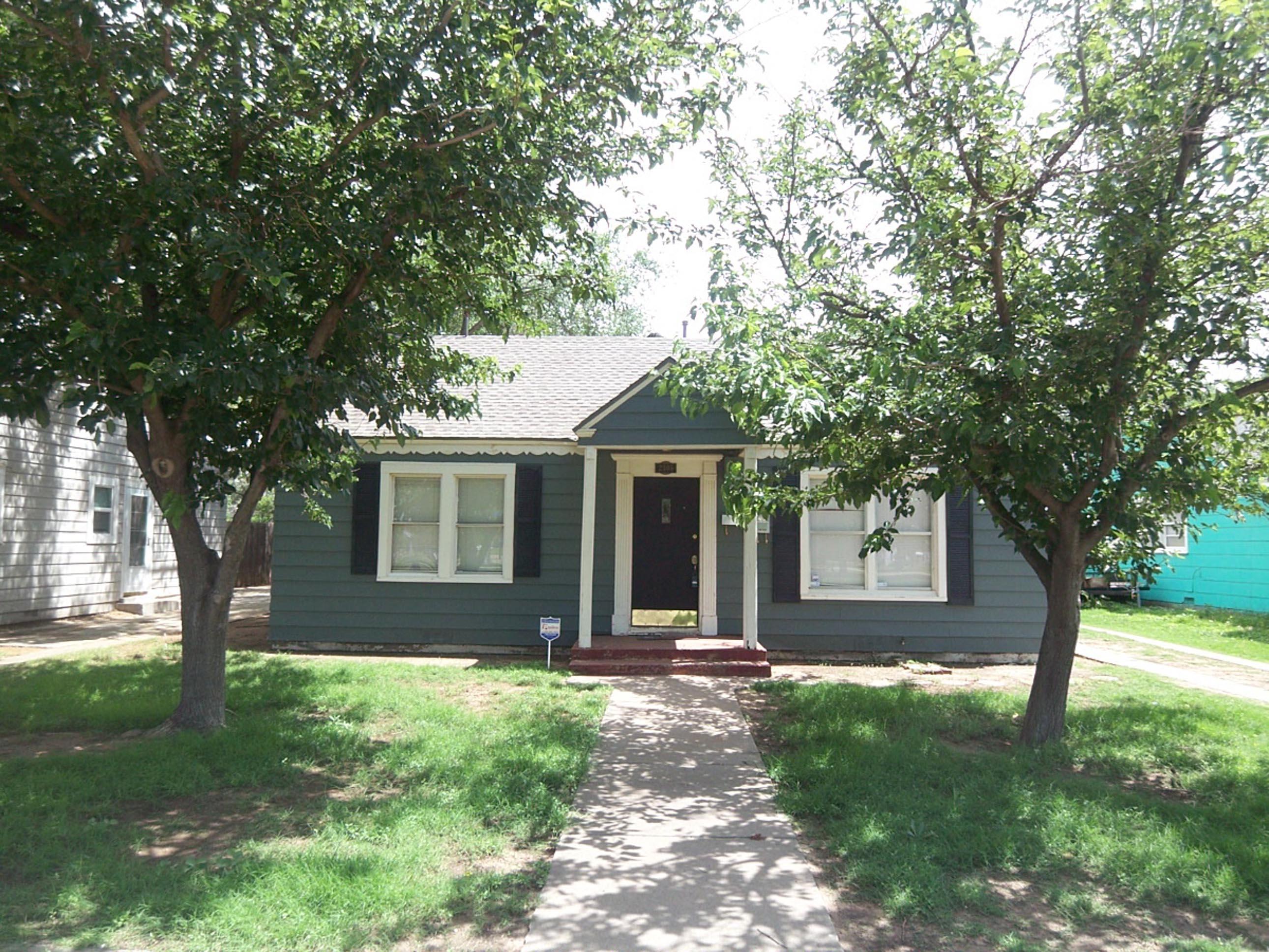 a view of a yard in front of a house with a large tree