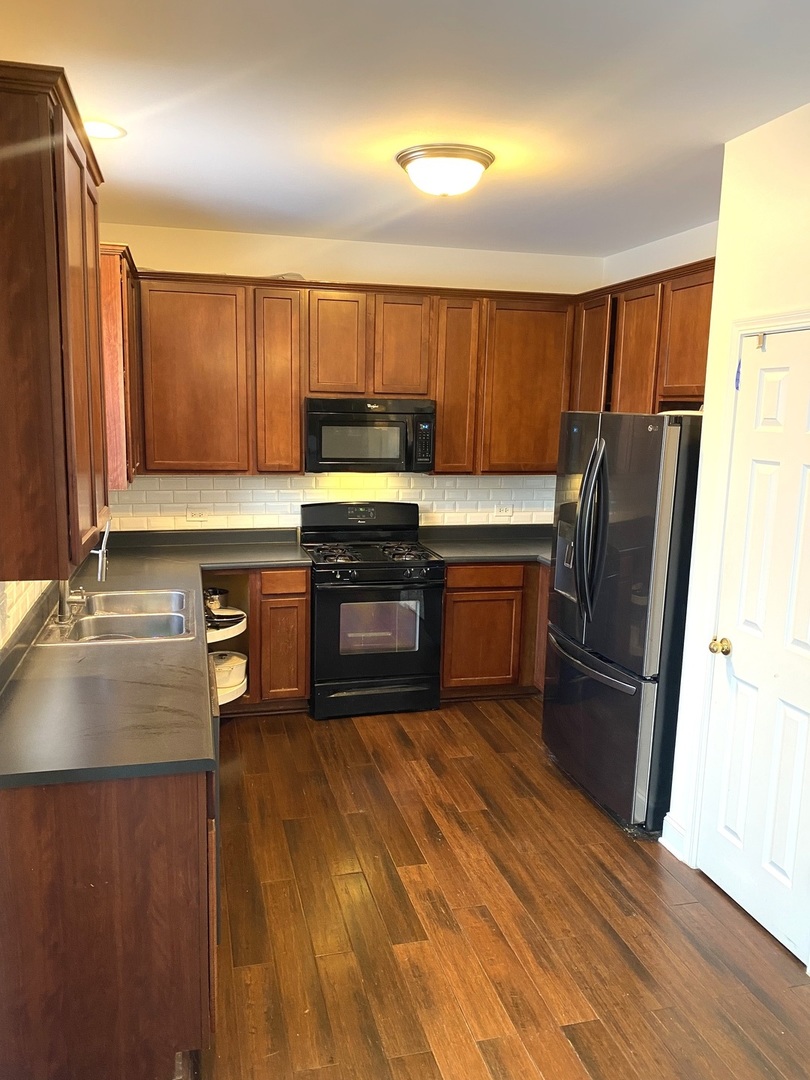 240 Copper Mountain Drive Gilberts, IL 60136 - Photo 19 of 30 a kitchen with stainless steel appliances granite countertop a refrigerator a sink dishwasher and wooden cabinets with wooden floor