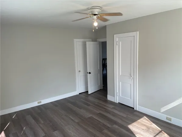 an empty room with wooden floor fan and windows