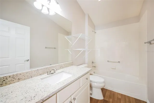 a bathroom with a granite countertop sink a toilet and shower