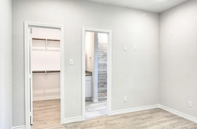 an empty room with wooden floor closet and windows
