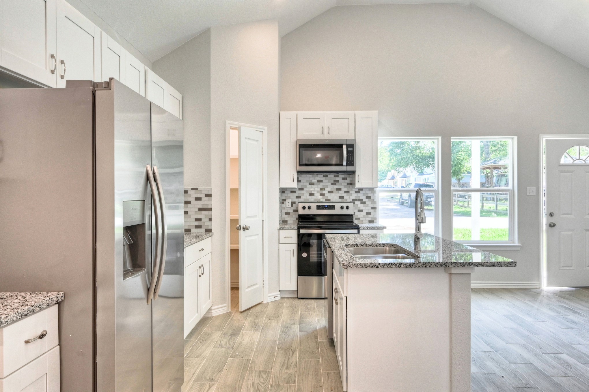 9812 Arbor Oak Willis, TX 77318 - Photo 5 of 40 a kitchen with kitchen island granite countertop a refrigerator and a stove top oven