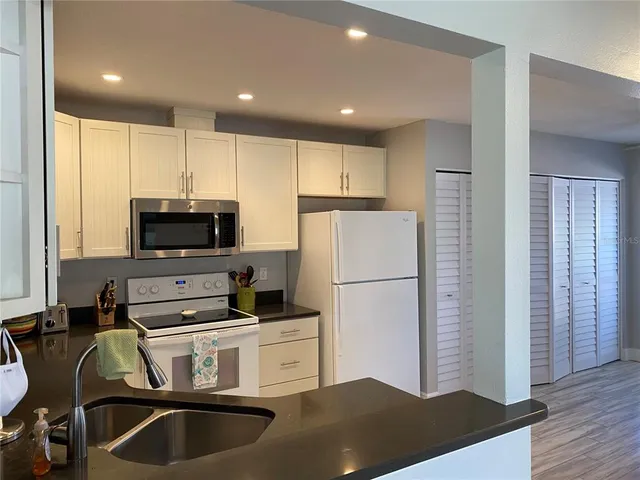 a kitchen with kitchen island a stove a refrigerator and a sink with wooden floor