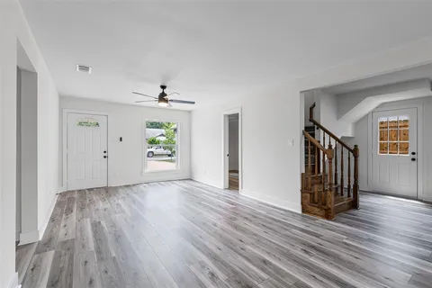 an empty room with wooden floor a ceiling fan and windows