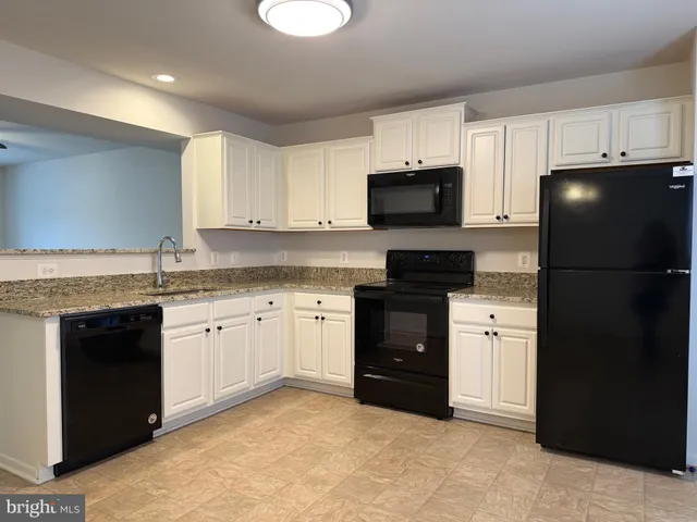 a kitchen with granite countertop a refrigerator stove top oven a sink and dishwasher