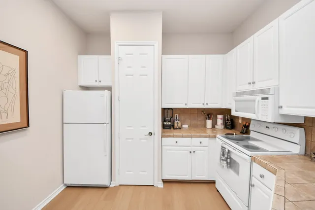 a kitchen with granite countertop white cabinets and white appliances