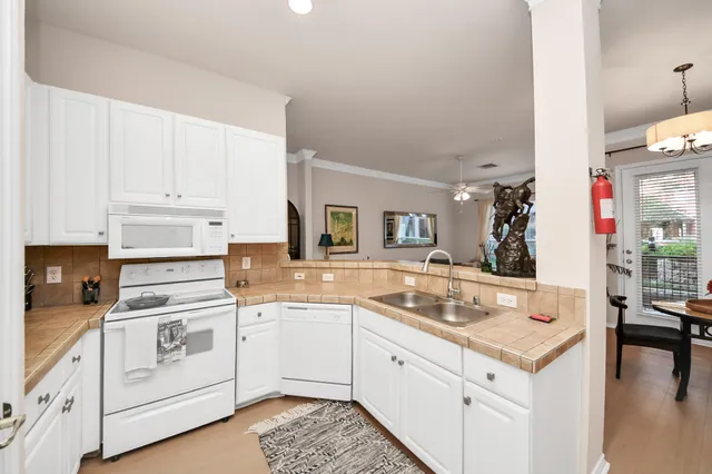 a open kitchen with granite countertop white cabinets and white appliances