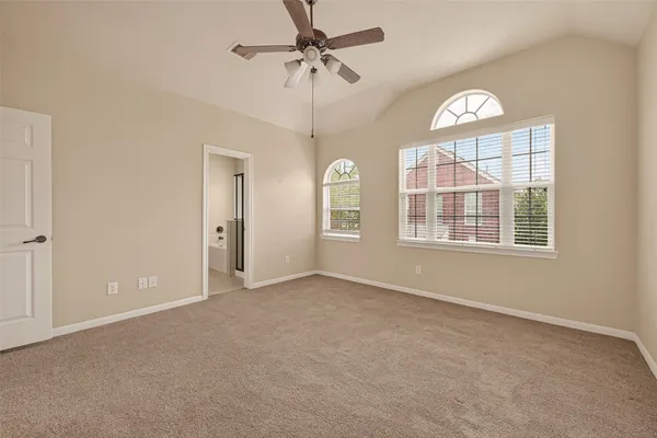 an empty room with chandelier fan and windows