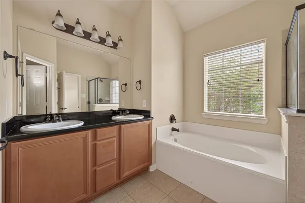 a bathroom with a granite countertop tub sink and mirror