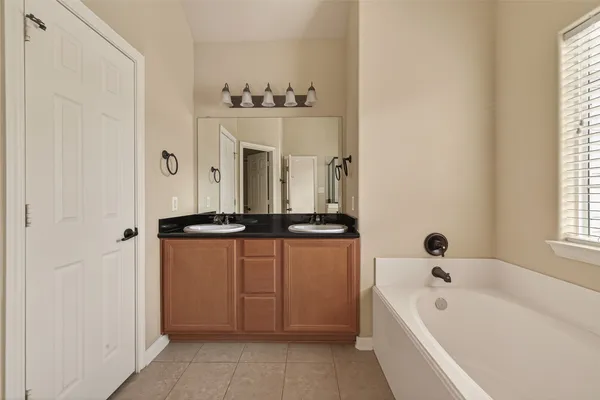 a bathroom with a bathtub a mirror a sink and a window