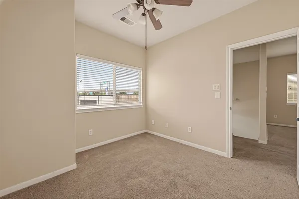 an empty room with windows and ceiling fan