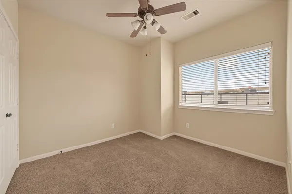 an empty room with windows and fan