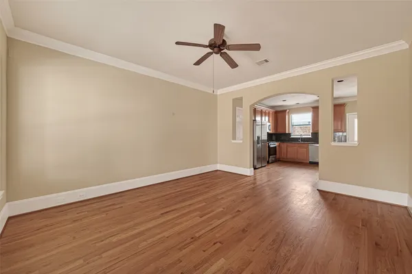 a view of a livingroom with wooden floor a ceiling fan and windows