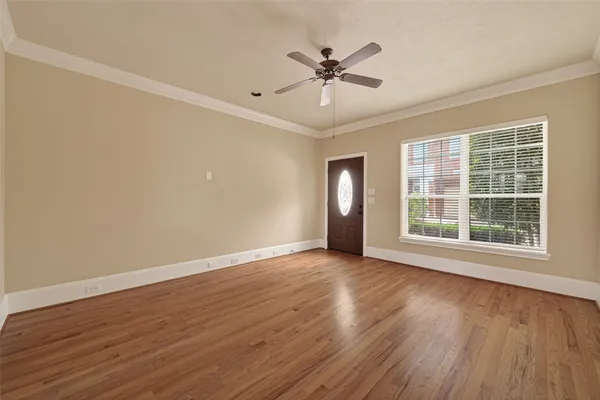 a view of an empty room with wooden floor and a window