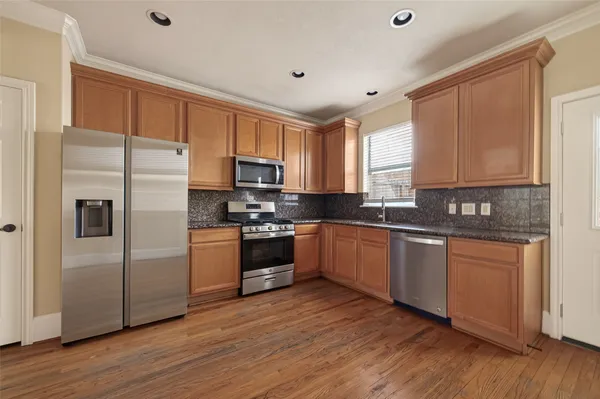 a kitchen with granite countertop a refrigerator stove a sink and dishwasher with wooden floor