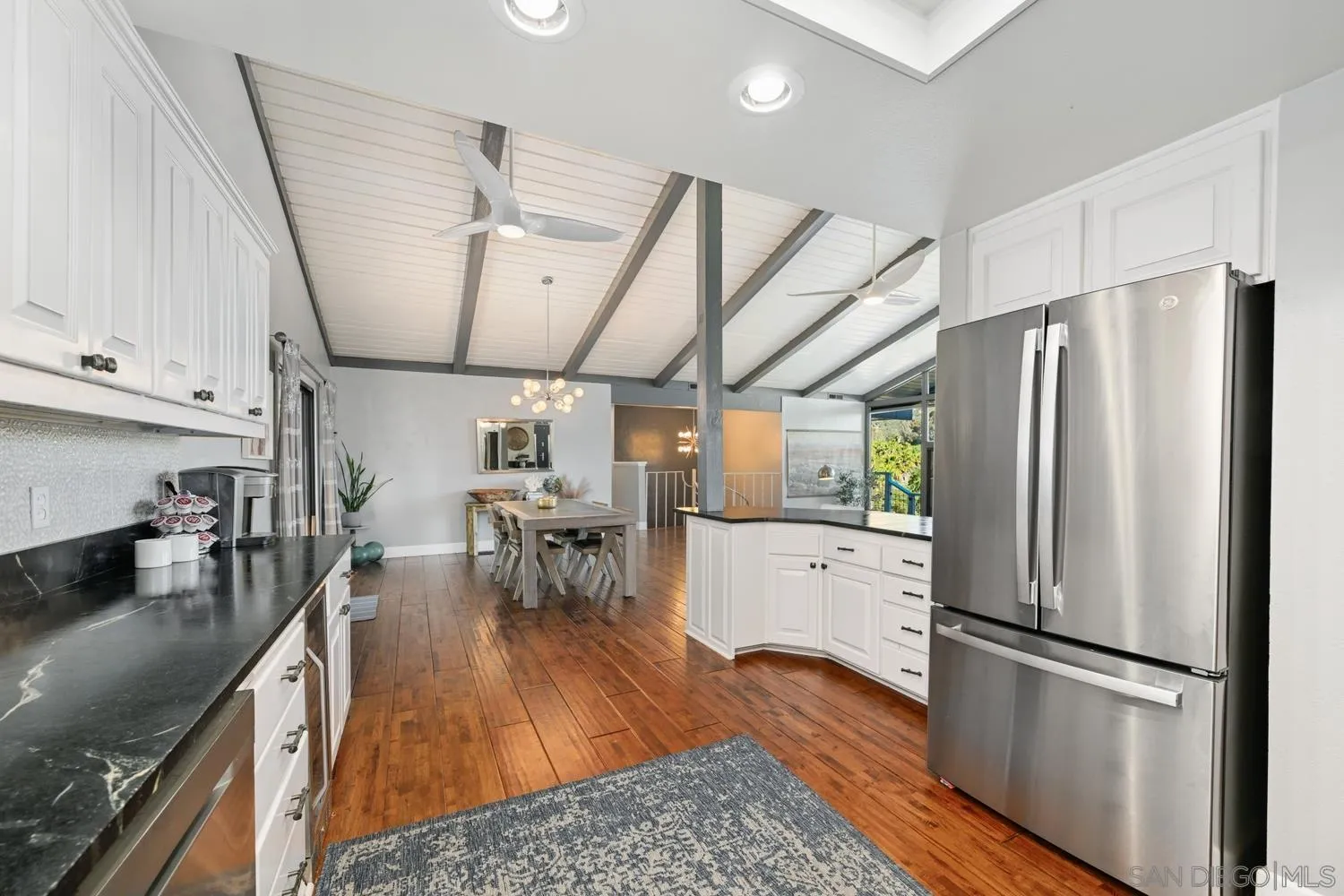26138 Jesmond Dene Road Escondido, CA 92026 - Photo 6 of 34 a kitchen with stainless steel appliances a refrigerator a sink dishwasher a stove and white cabinets with wooden floor
