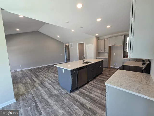 a large kitchen with stainless steel appliances a large counter top a stove and a refrigerator