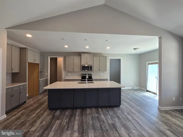 a living room with stainless steel appliances kitchen island hardwood floor sink and stove