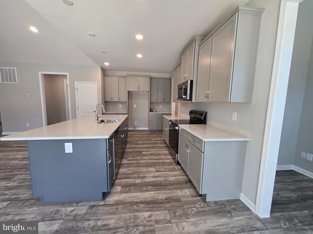 a large kitchen with kitchen island a sink a counter top space and stainless steel appliances