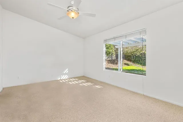 an empty room with a window and a fan