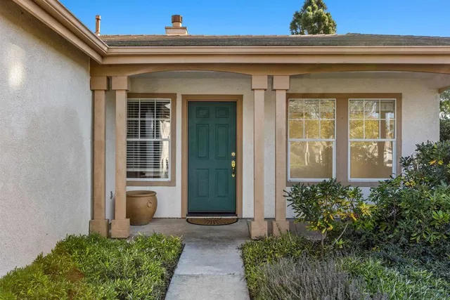a view of a house with potted plants and a table and chair