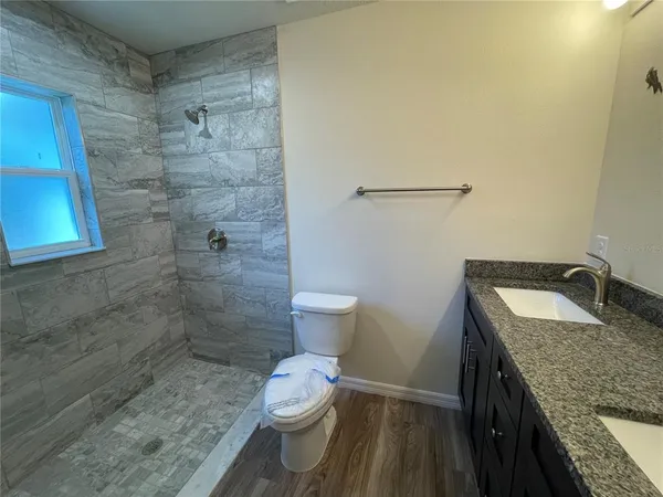 a bathroom with a granite countertop sink a toilet and a shower