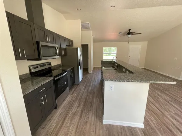 a kitchen with granite countertop wooden floors and stainless steel appliances