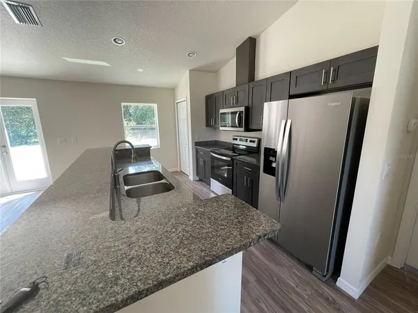 a kitchen with stainless steel appliances granite countertop a stove a refrigerator and a sink