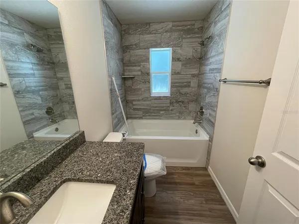 a bathroom with a granite countertop bathtub shower and sink