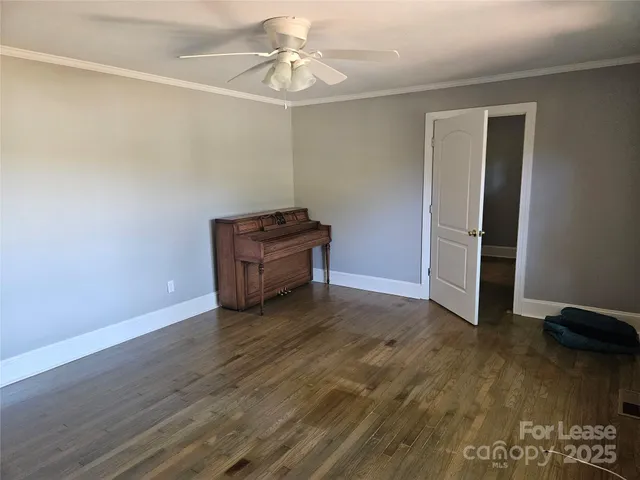 an empty room with wooden floor closet and windows