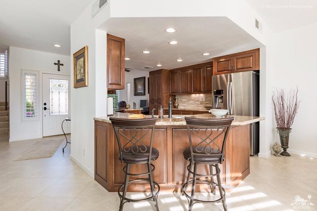 a kitchen with stainless steel appliances kitchen island granite countertop a refrigerator and a stove top oven