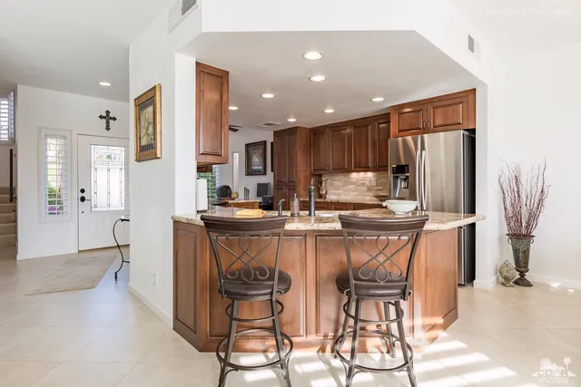 a kitchen with stainless steel appliances kitchen island granite countertop a refrigerator and a stove top oven