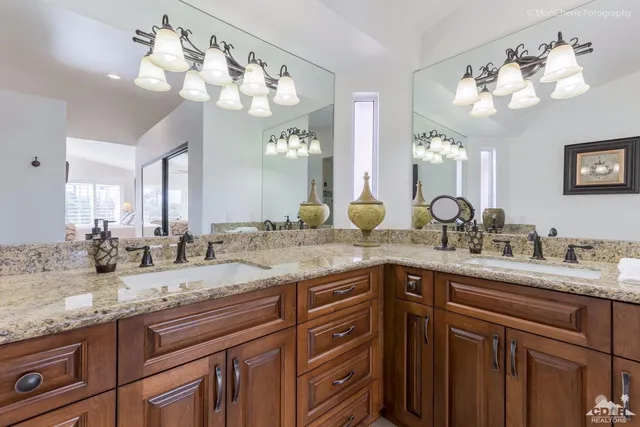 a bathroom with a granite countertop double vanity and a mirror