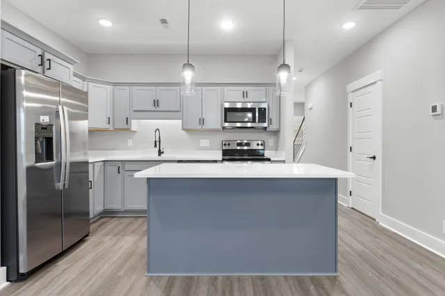 a kitchen with kitchen island a counter top space a sink appliances and cabinets